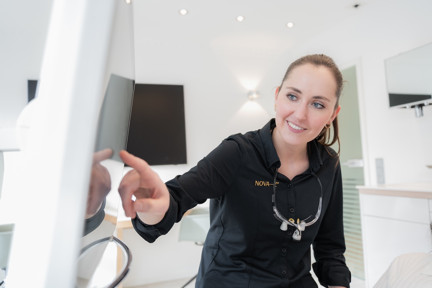 Eine Zahnärzin von NOVA-Z zeigt einer Patientin etwas auf einem Bildschirm