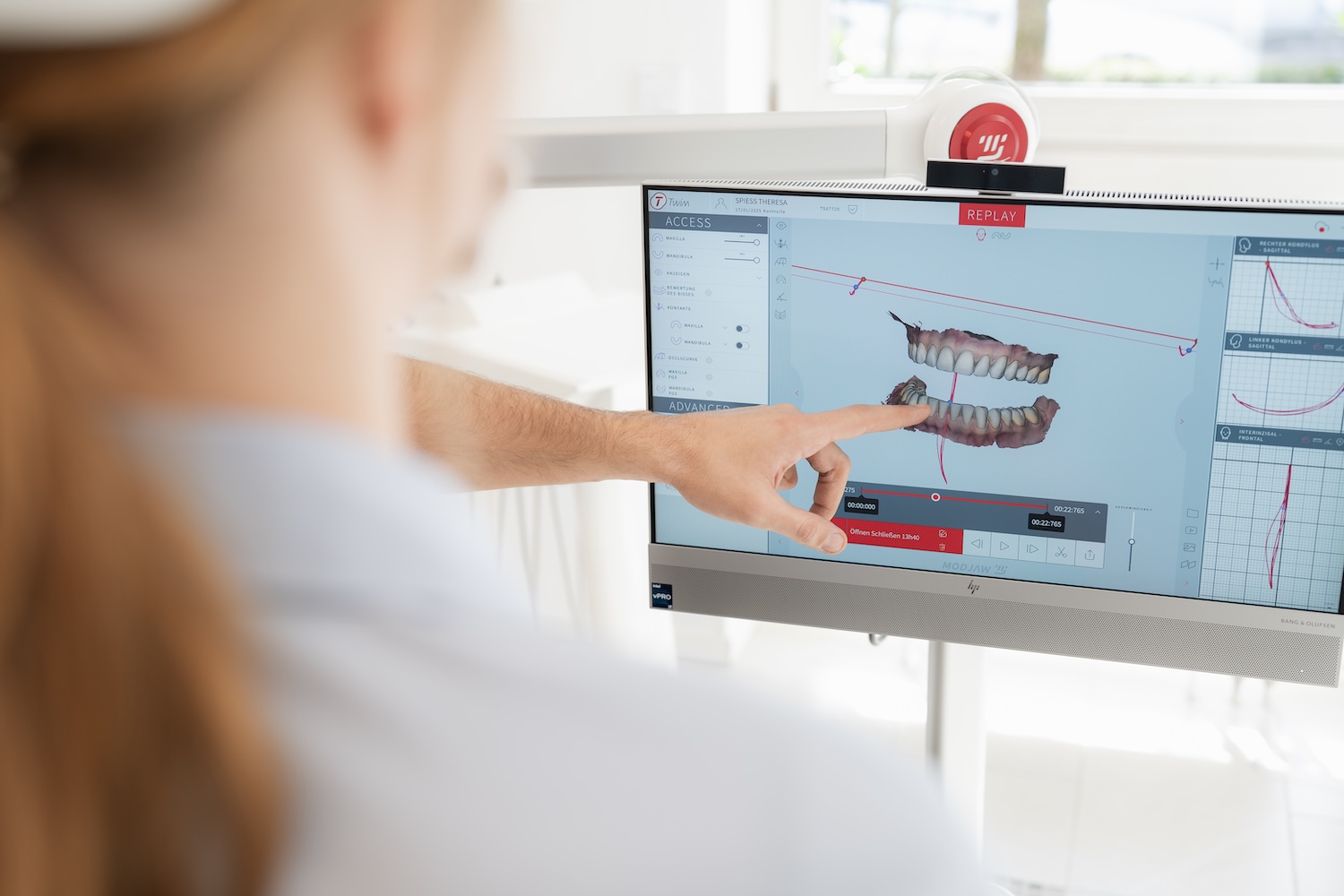 Zahnarzt Dr. Denis Novakovic zeigt einer Patientin ihr Gebiss auf einem Bildschirm im Rahmen einer Kiefergelenksdiagnostik