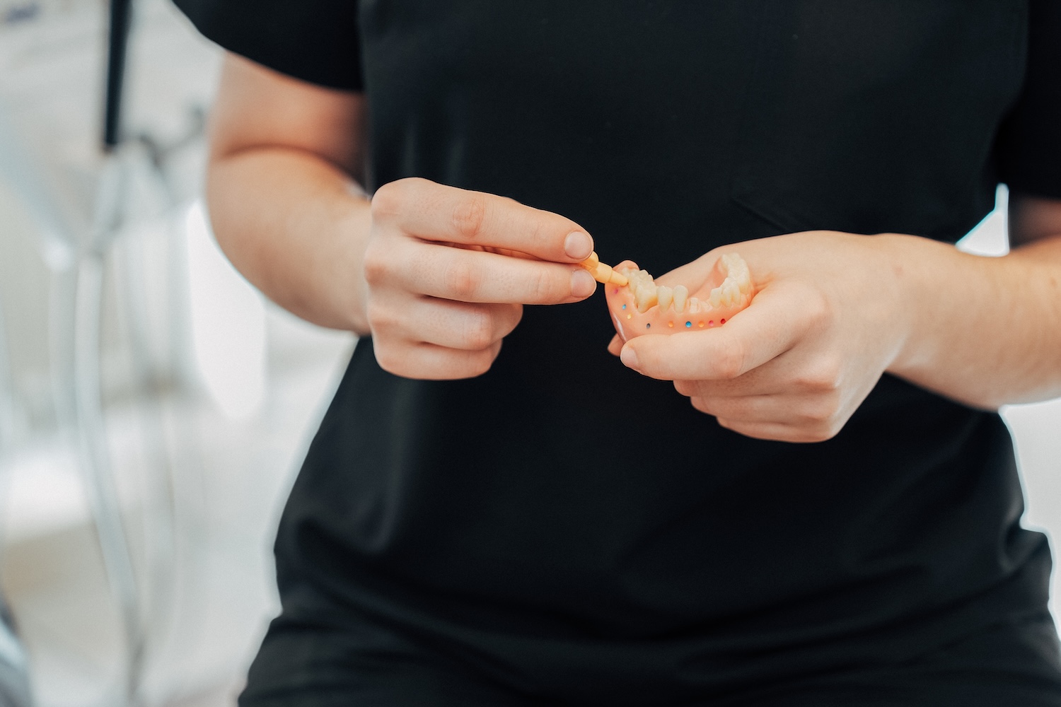 Detailansicht der Hände einer Mitarbeiterin von NOVA-Z, sie hält ein Gebissmodell in den Händen