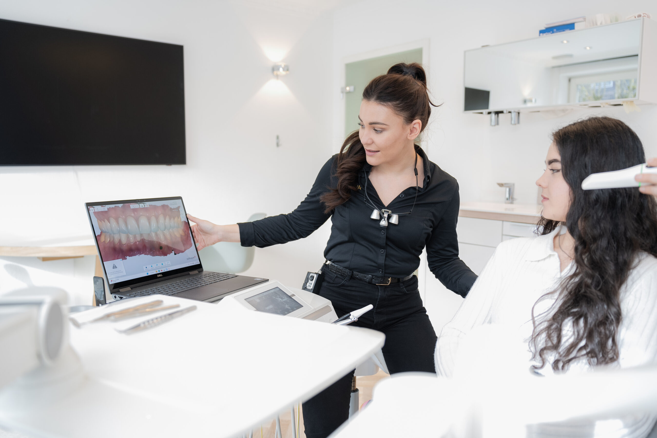 Zahnärztin Theresa Spiess zeigt einer Patientin eine 3D-Aufnahme ihres Gebisses an einem Laptop